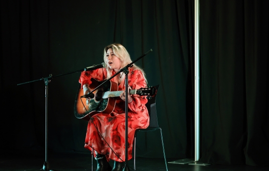 A contestant sings and plays guitar on the SLC stage