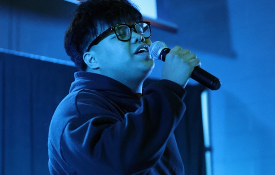 A contestant sings into a microphone on the SLC stage