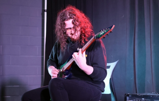 A contestant plays electric guitar on the SLC stage