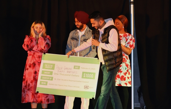 Rishi hands a $1000 giant cheque to the winning contestant