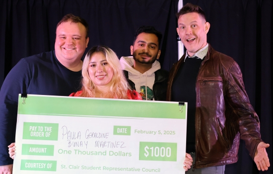 First place winner smiles and poses with the judges while holding the giant cheque