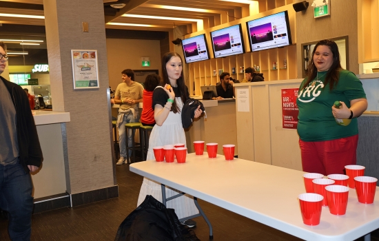 Students and student staff gather around the lemonade pong table