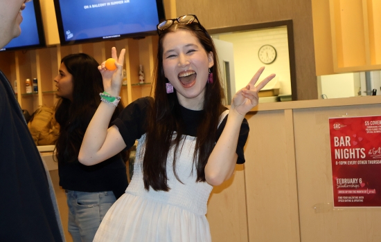 A student throws up double peace signs and smiles for the camera