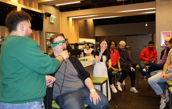 A student is blindfolded for UpDating as Ali holds a microphone for them