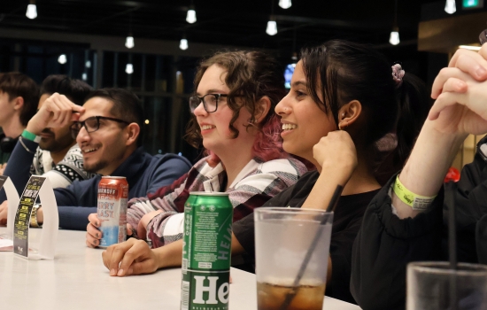 A row of students sit and watch UpDating while enjoying beverages