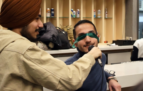 A student is blindfolded for UpDating as Pratham holds a microphone for them