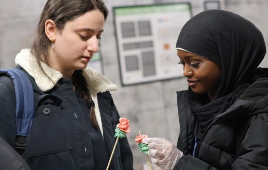 Two students hold up sour candy roses