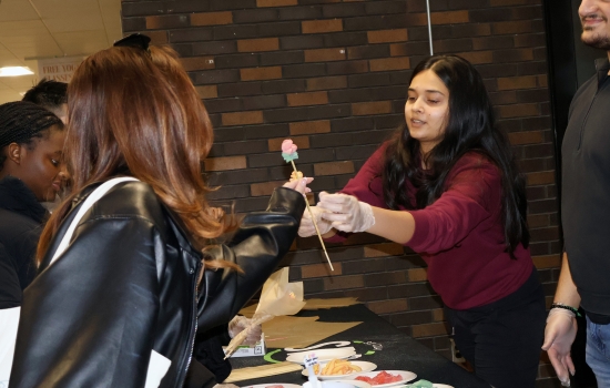 Harnoor passes a candy rose to a student