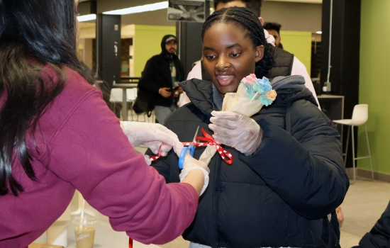 Harnoor passes a bouquet of candy roses to a student