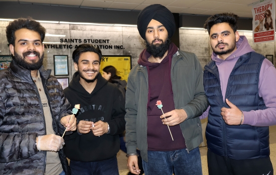 Four students post for the camera with their roses