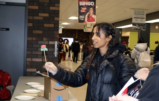 A student smiles while holding a sour candy rose