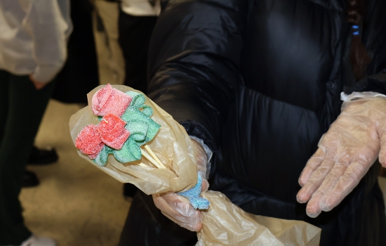 A student shows off a sour candy rose bouquet complete with paper and ribbon