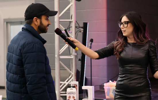A student speaks into a microphone held by Alisha