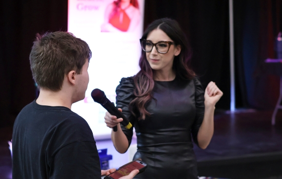 A student speaks into a microphone held by Alisha
