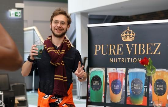 A student poses with the Pure Vibez banner