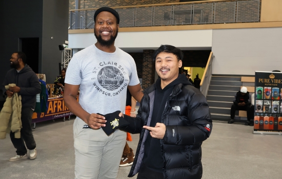 A student receives an SRC touque from a student staff member