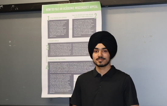 Pratham stands in front of a poster outlining the process for Academic Misconduct appeals