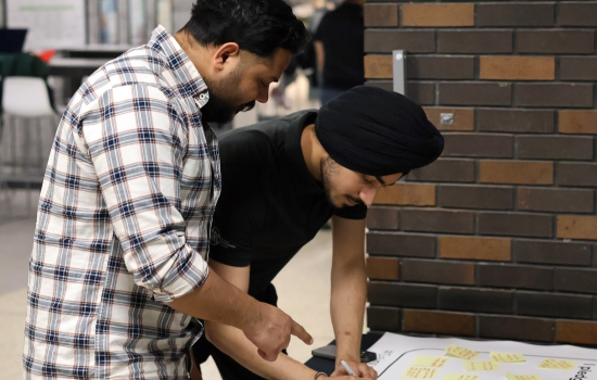Pratham speaks with a student while writing on the pledge poster