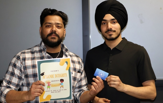 Pratham hands a student a gift card while the student holds up the event flyer