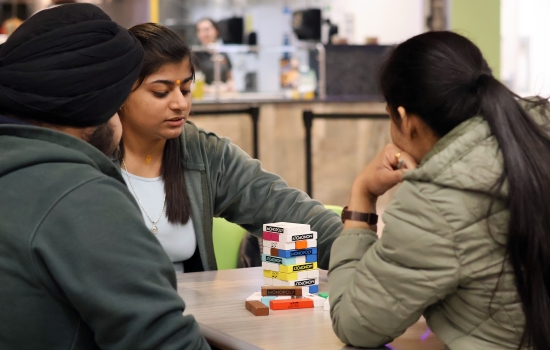 A group of three students play Monopoly Jenga
