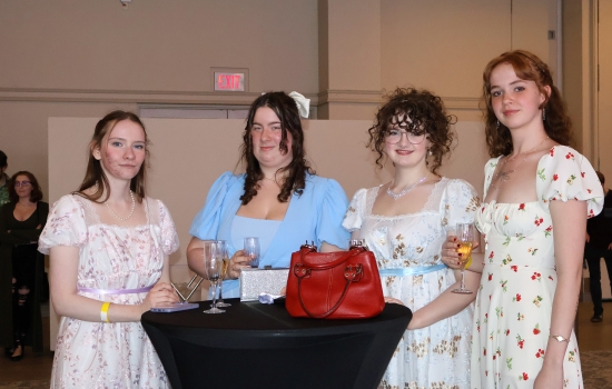 A group of guests stand at a cocktail table and pose for the camera
