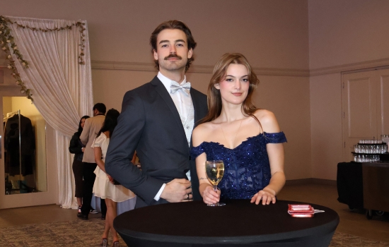 Two guests stand at a cocktail table and pose for the camera