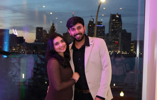 Two guests pose for the camera in front of the Detroit skyline
