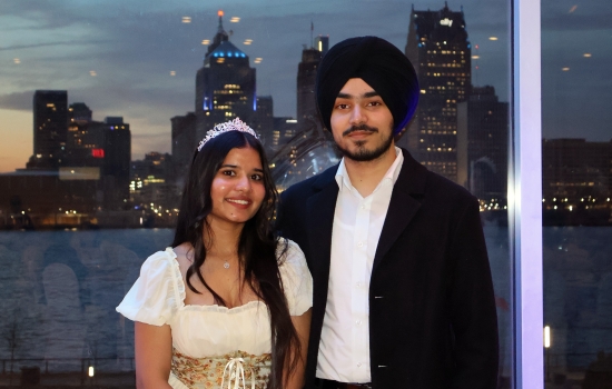 Pratham and his date pose in front of the Detroit skyline