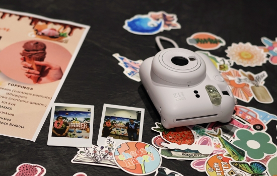 A closer look at the table with stickers, a list of toppings, camera and polaroids