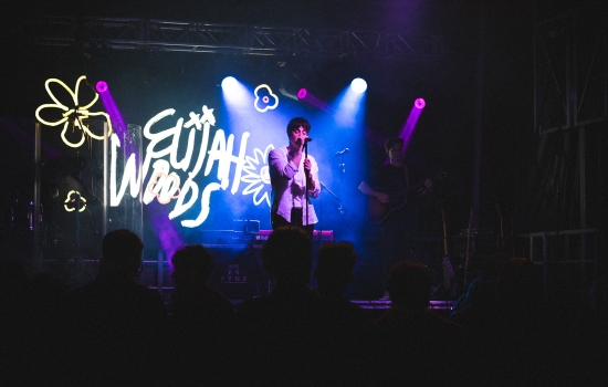Elijah Woods smiles and performs on a stage