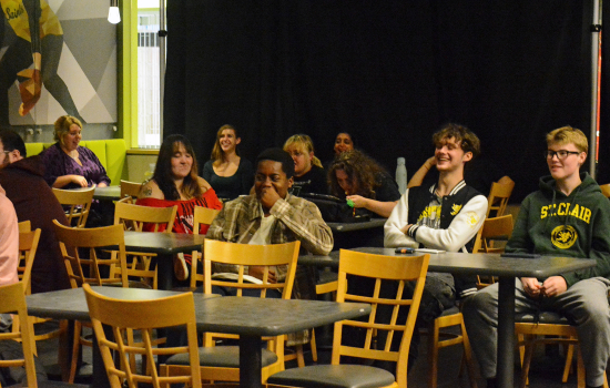 an audience of college students has a laugh in a pub environment