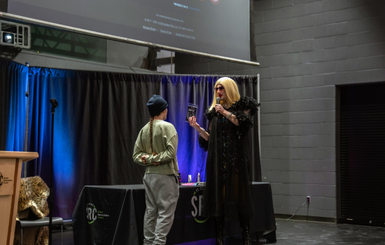 A student on stage with the drag queen host