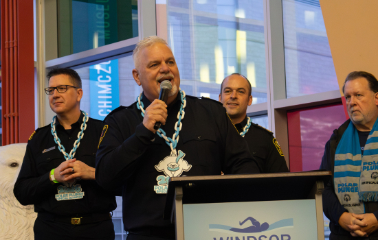 3 gentlemen wearing polar plunge necklaces, one addresses the crowd