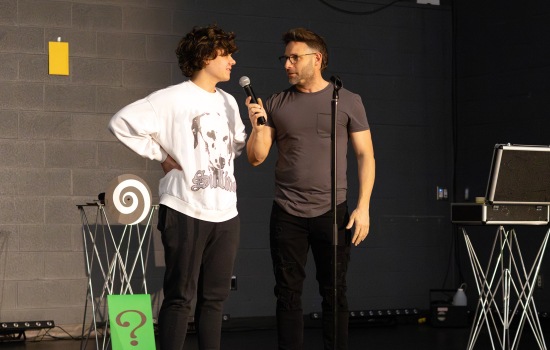 Eric Leclerc holds the mic for a student volunteer on stage