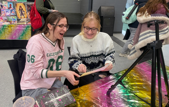 Two students laugh and smile at their caricature reveal