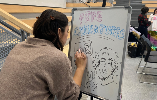 The caricature artist creates her sign on a draw erase board