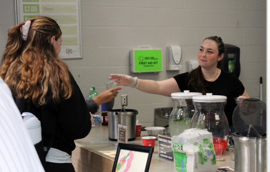 src staff hands a mocktail to a student