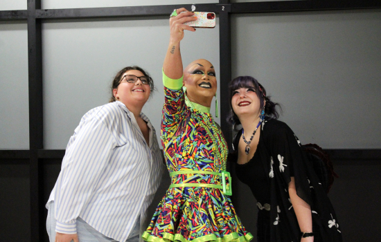 Drag Queen Sabin takes a selfie with 2 students