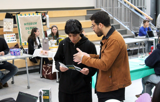 A club member discusses their club with a student looking at a brochure