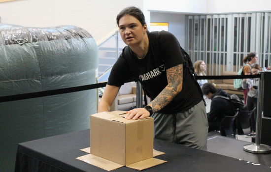 A student feels inside a mystery box